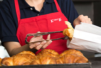 Kabhi B bakery staff serving fresh croissants with care.